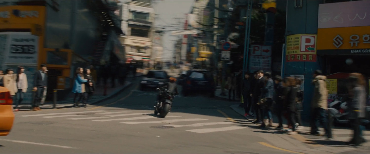The Black Widow on a motorcycle turns a corner.