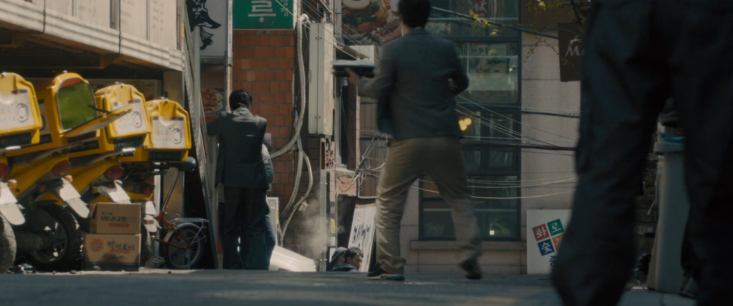 The Black Widow on a motorcycle speeds through a narrow street.