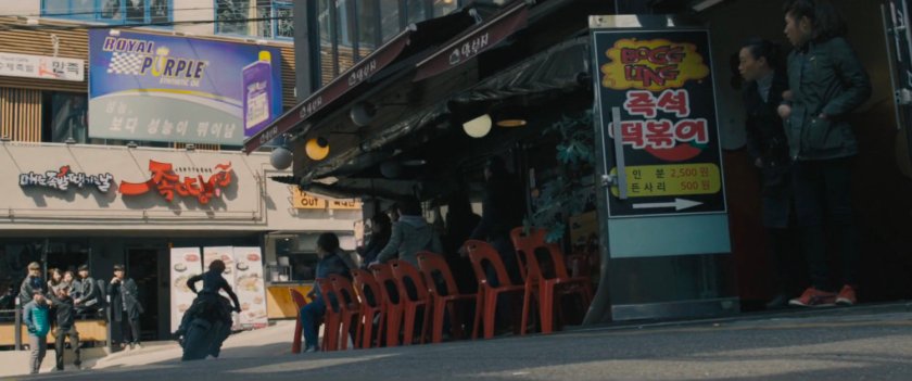 The Black Widow on a motorcycle speeds through a narrow street.