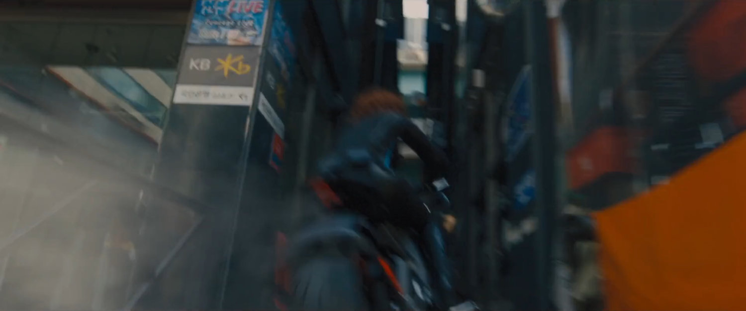 The Black Widow on a motorcycle speeds through a narrow alley.