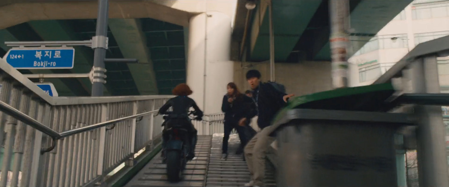 The Black Widow on a motorcycle speeds up a staircase.