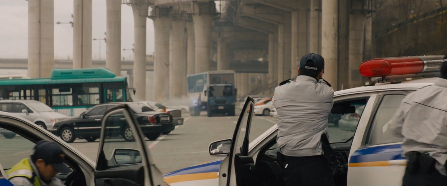 Police take aim at truck traveling through parking lot under expressway.