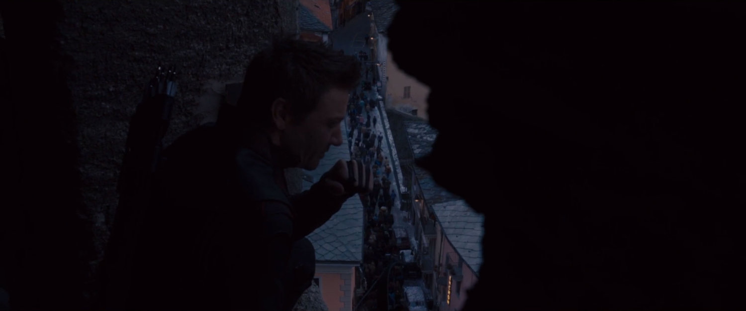 Hawkeye looks down over street with civilians evacuating.