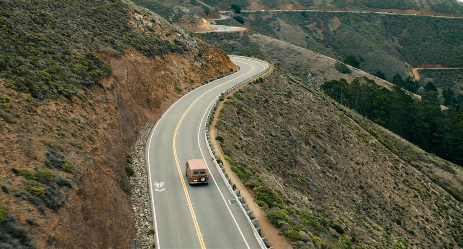 Van driving on twisty hillside road.
