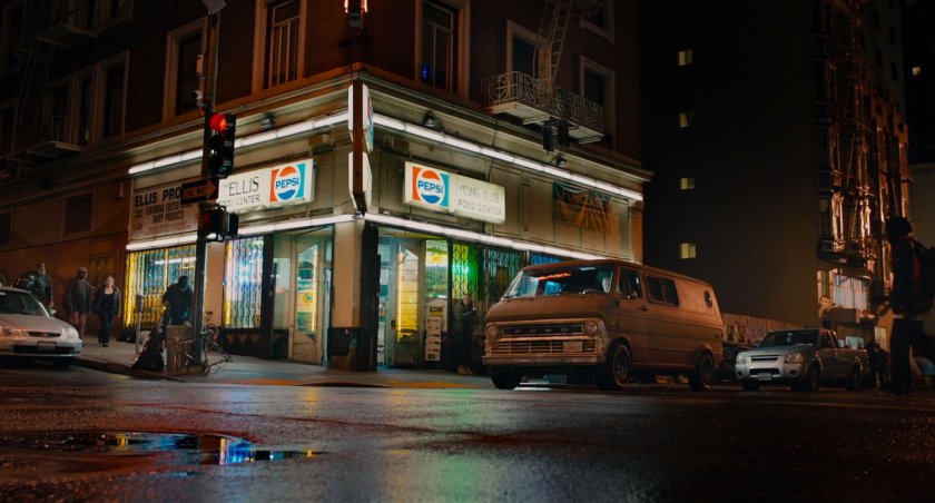 Nighttime exterior of The Milgrom Hotel building from intersection.