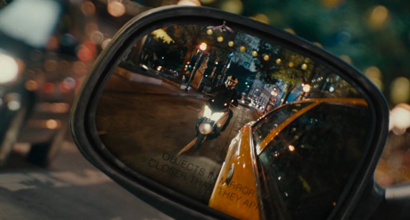 Close-up reflection of moped in taxi cab side mirror.