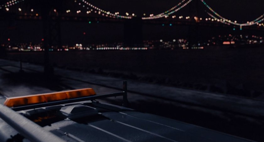 Nighttime shot of road with Bay Bridge in background.