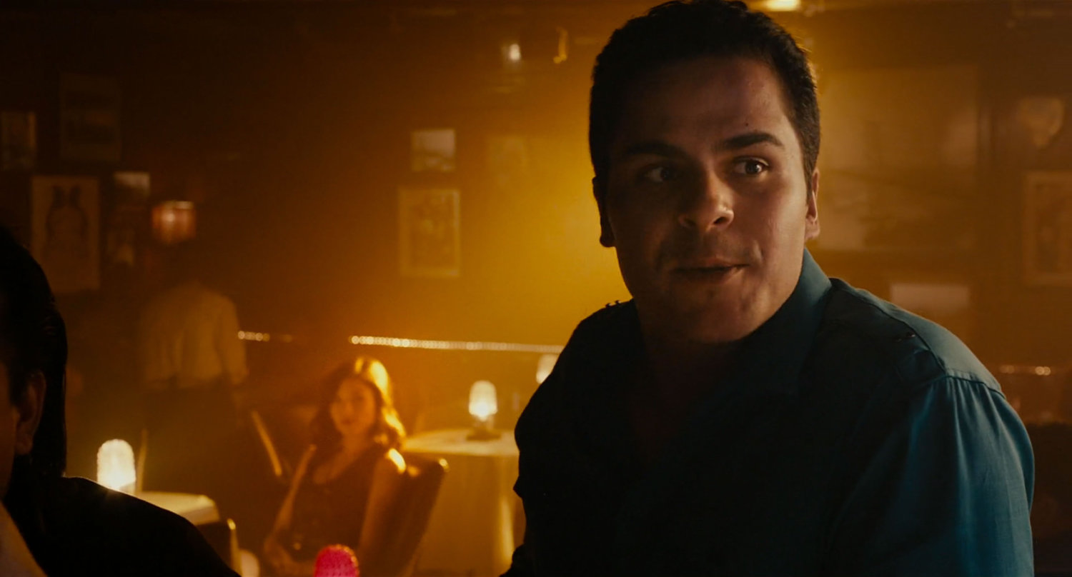 A man at a bar in a smoky Jazz club.