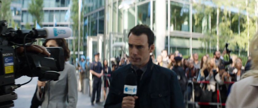 Reporters stand in front of crowds outside Uniter Nations building.