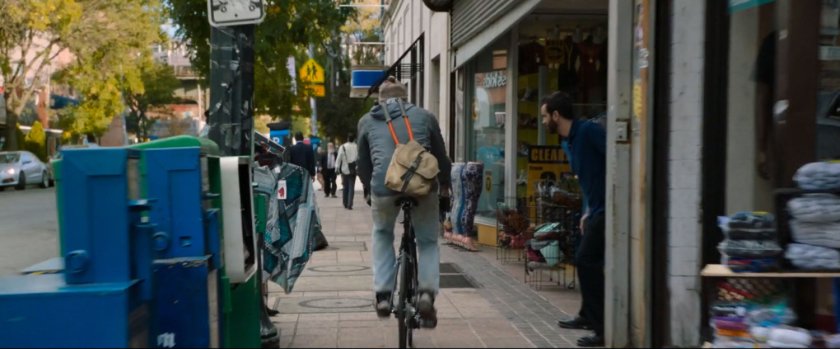 Man on bike riding on sidewalk.