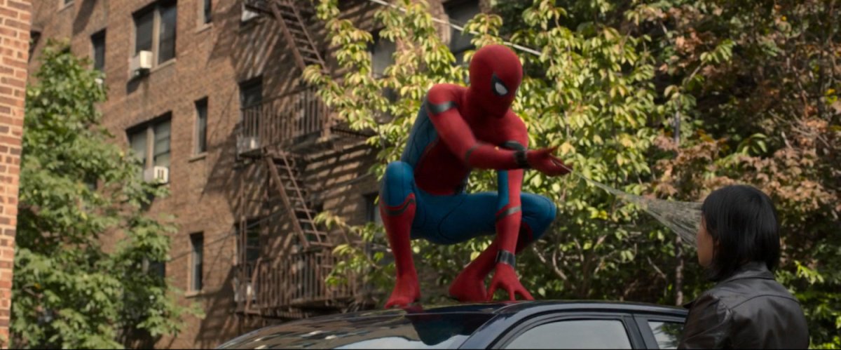 Spider-Man on top of car, webbing man in face.
