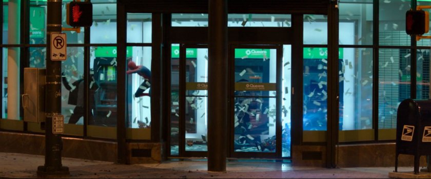 Exterior of Queen Community Bank with Spider-Man fighting robbers inside.