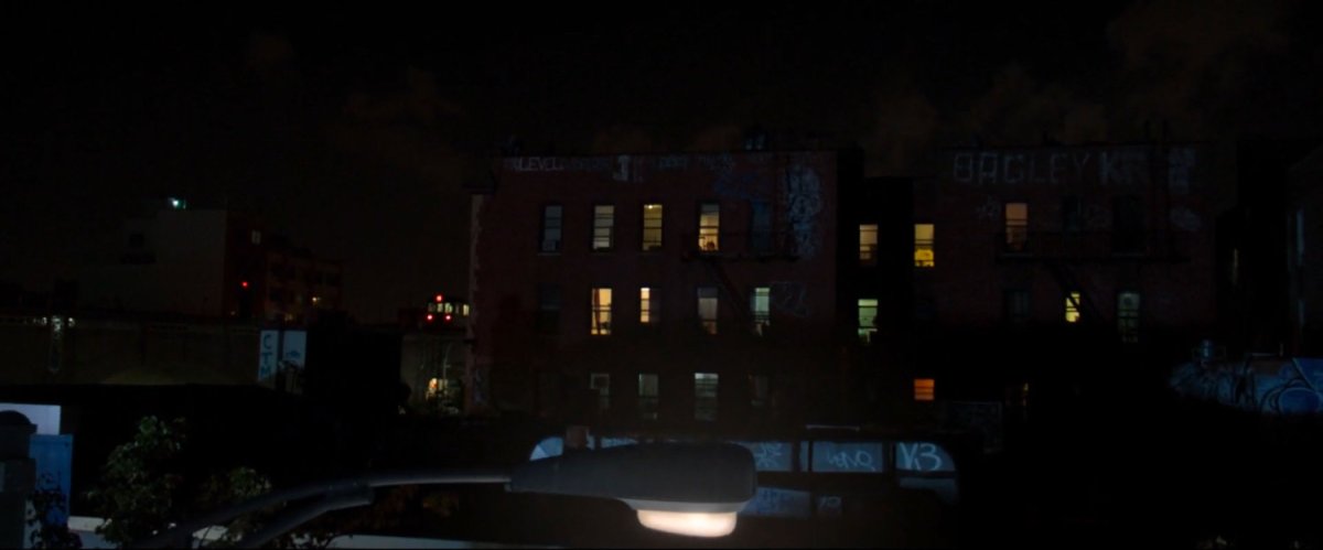 Spider-Man walking on a roof at nighttime.