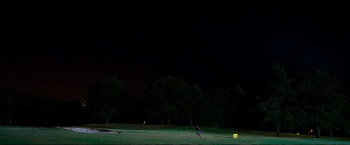 Wide shot of Spider-Man running across golf course at night.