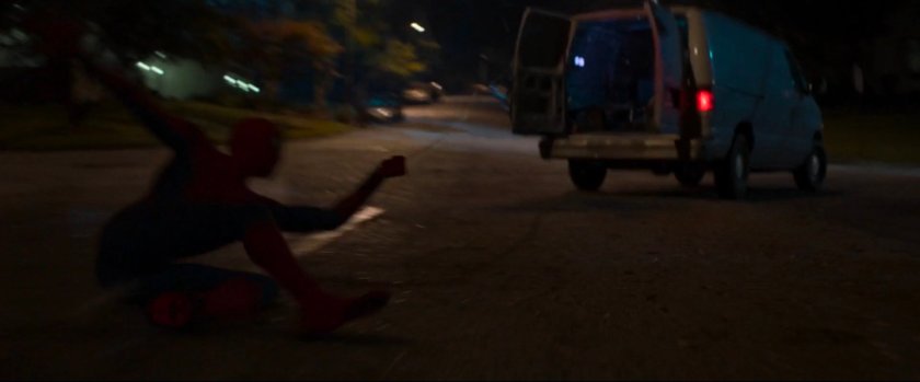 Spider-Man dragged by webbing behind van.