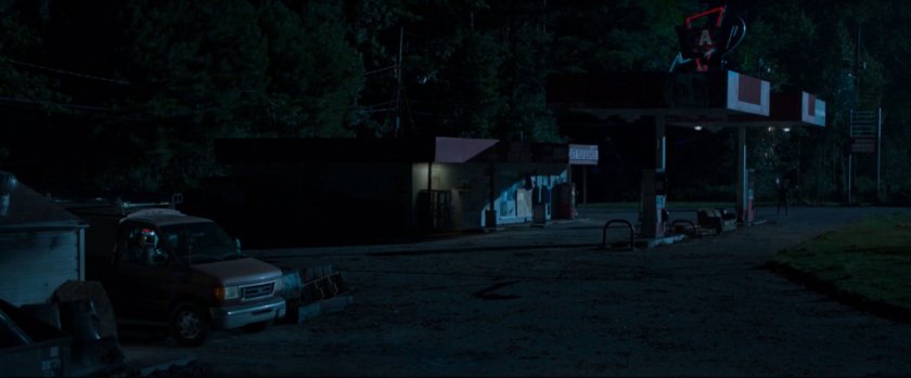 Peter spies on a van at a derelict gas station.
