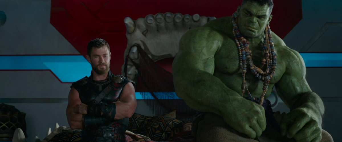 Thor and the Hulk sit on the edge of a bed.