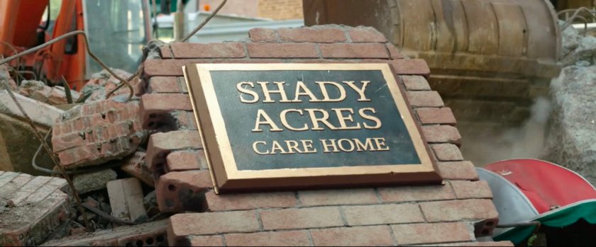 Care home sign on wreckage. Text: Shady Acres Care Home.