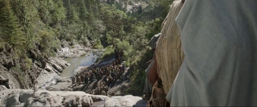 View of people on rocky path near waterfall.