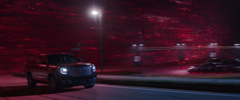 A Black SUV outracing a red energy curtain following it.