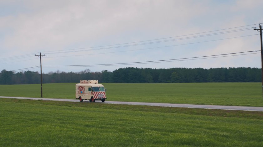 Ice Cream truck driving on country road.