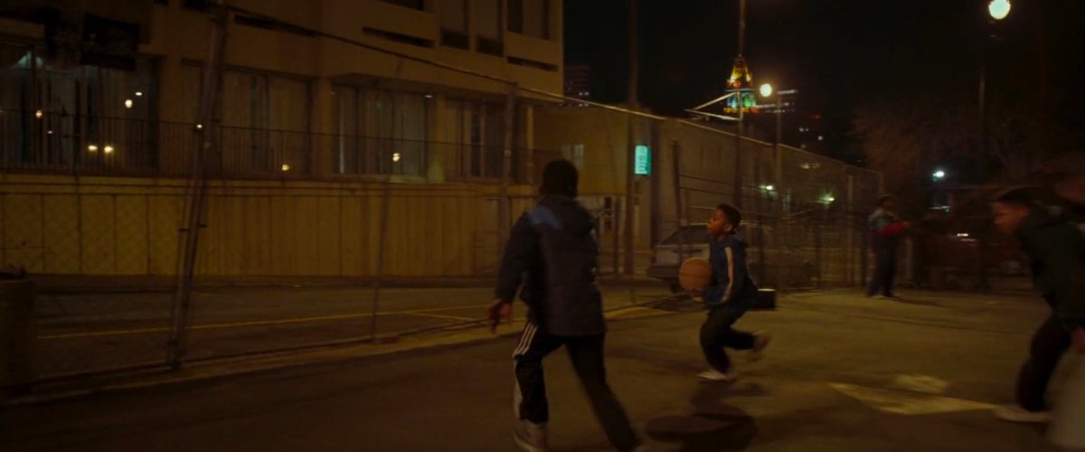 Two young boys playing basketball in a parking lot.