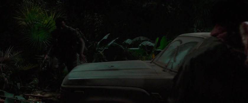 Soldiers by jeep in an African forest at night.
