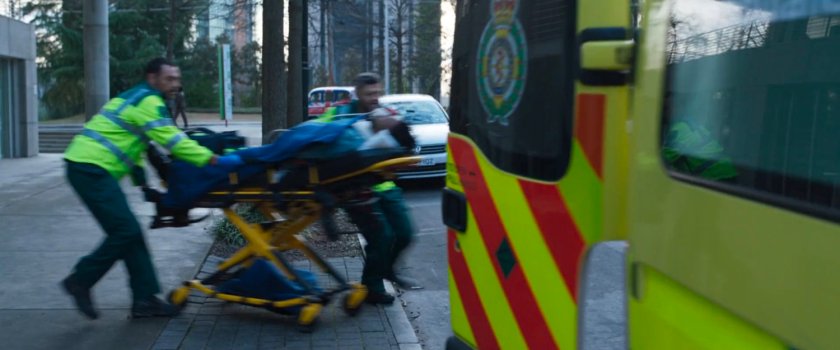 Two men rush a patient into an Ambulance.