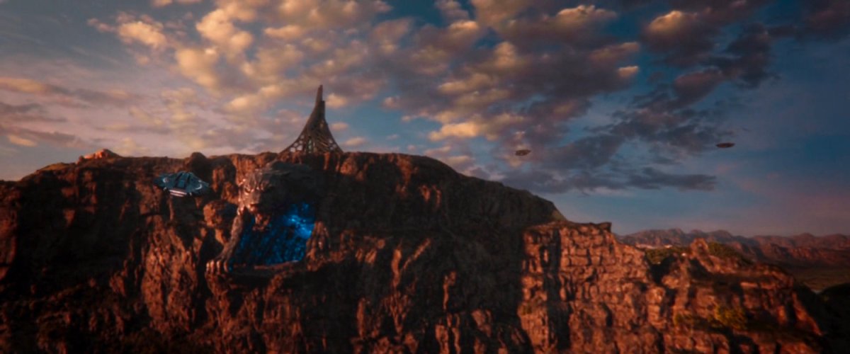 Wide view of Mount Bashenga which has a giant panther figure hutting from the side of the cliff.