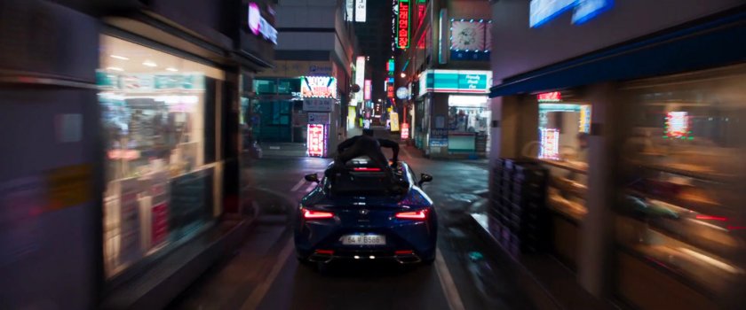 Black Panther atop a car driving through a narrow Busan street.
