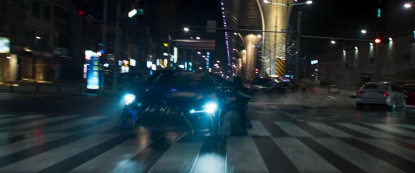 Black Panther hangs off the side of a car on a wide Busan road.