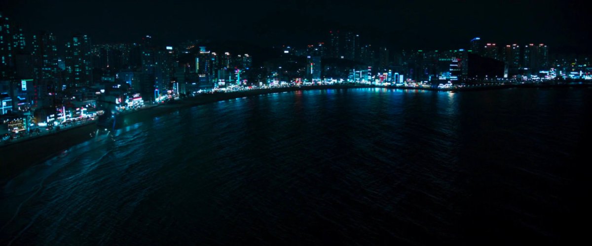 Aerial view of Busan shoreline at night with buildings lit up.