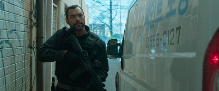 A man with gun walks past a white van.