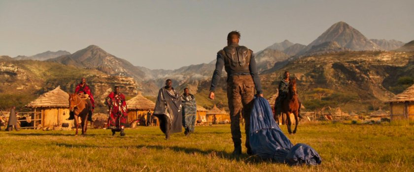 Killmonger approaches members of the Border Tribe with their huts in the background.