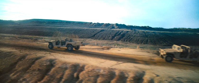 Humvees racing across desert road.