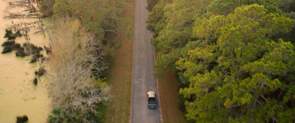 A car on a tree lined highway.