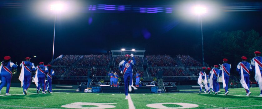 A drum major and marching band on a football field.
