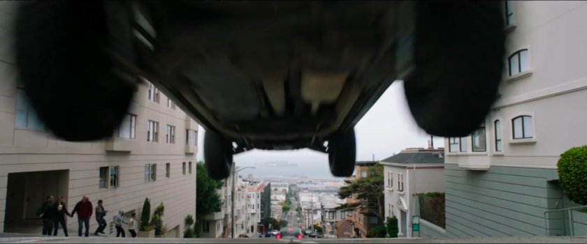 A white car leaping over a San Francisco intersection.
