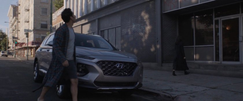 Scott Lang crossing in front of parked car towards building.