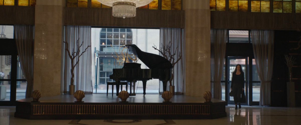 Hope enters a large room with a piano and big window facing the street.