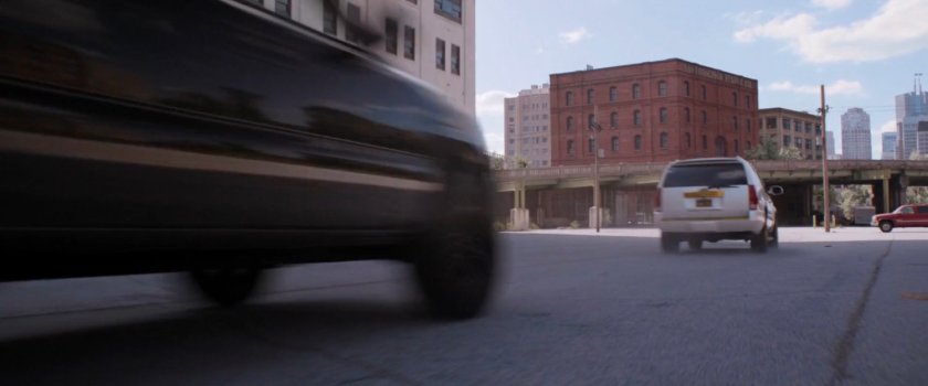 Car chase through parking lot of industrial area.