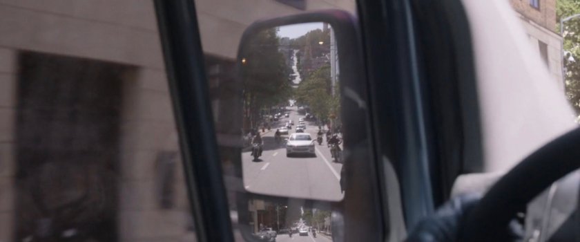 Motorcycles follow the van as seen in the side mirror.