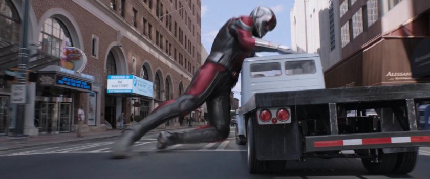 Giant-Man pushing on front of flatbed truck to stop it.