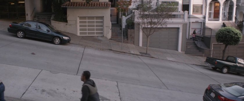 A miniature car drives down a hilly San Francisco street.