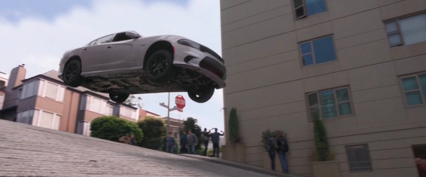 A white car leaping over a San Francisco intersection.