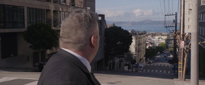 A man looks down a hilly street.