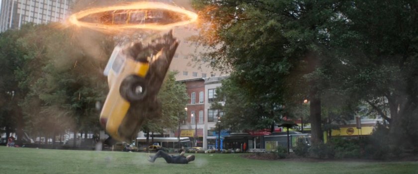 Half a taxi cab falls from a portal into a park.