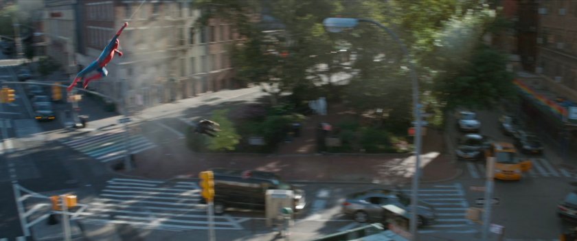 Wide angle of Spider-Man swinging over a New York square.