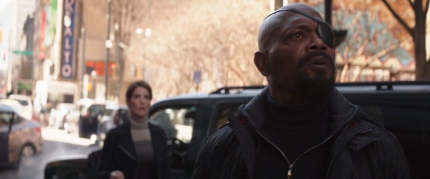 Maria Hill and Nick Fury look up into sky from city street.