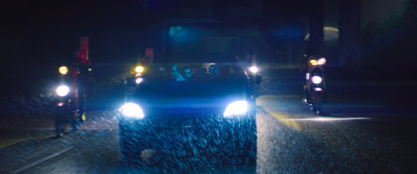Vehicles on a rainy nighttime road heading towards Madripoor.